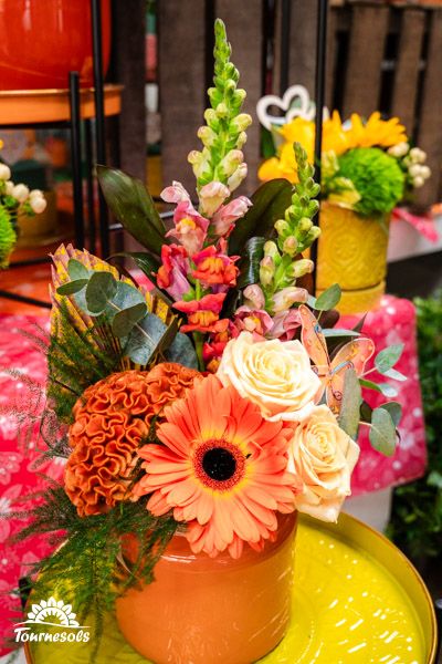 Arrangement floral aux tons colorés orange avec gerbera et roses, dans un pot orange.